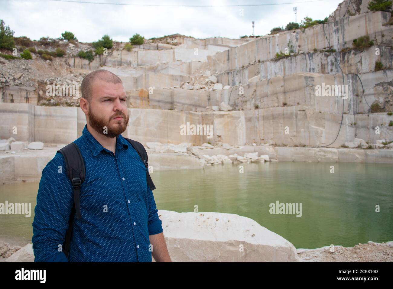 Kahlbärtiger Mann, der in einem verlassenen Steinbruch auf der Insel brac in kroatien steht. Blick in die Ferne mit einem ernsthaften Blick besorgt Stockfoto