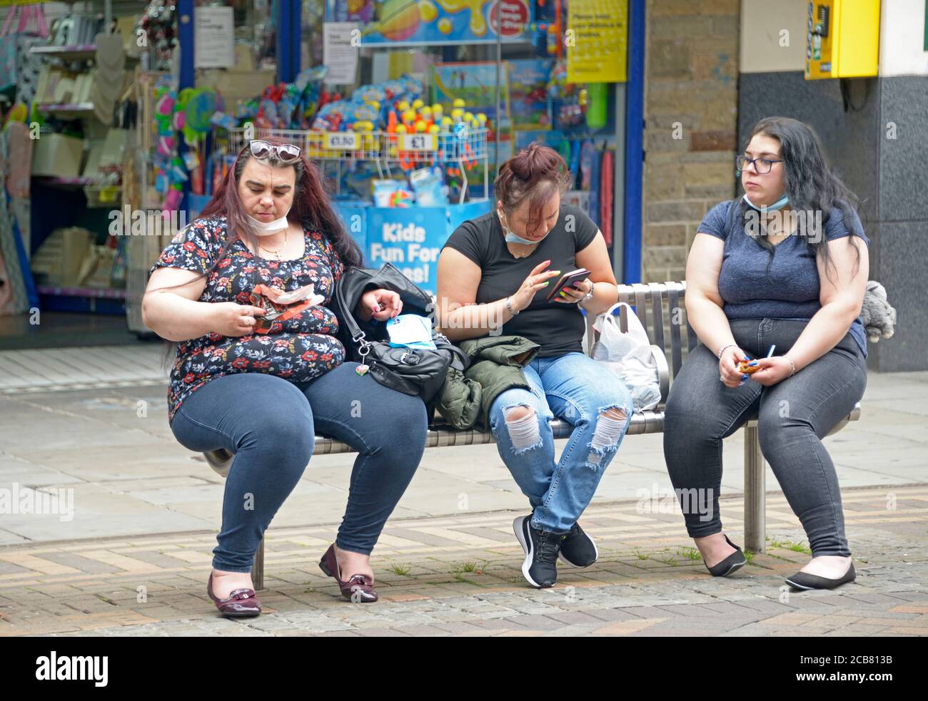 Drei übergewichtige Frauen sitzen und überprüfen Telefone Stockfoto