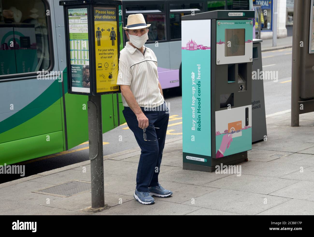 Mann in Maske, gelehnt an die Bushaltestelle. Stockfoto
