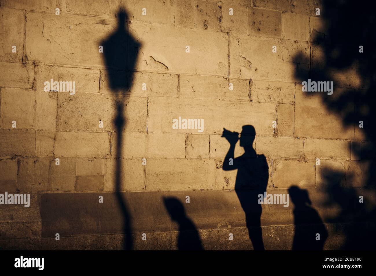 Schatten des Fotografen an der Steinmauer. Junger Mann fotografiert alte Straße bei Sonnenuntergang. Zürich, Schweiz. Stockfoto