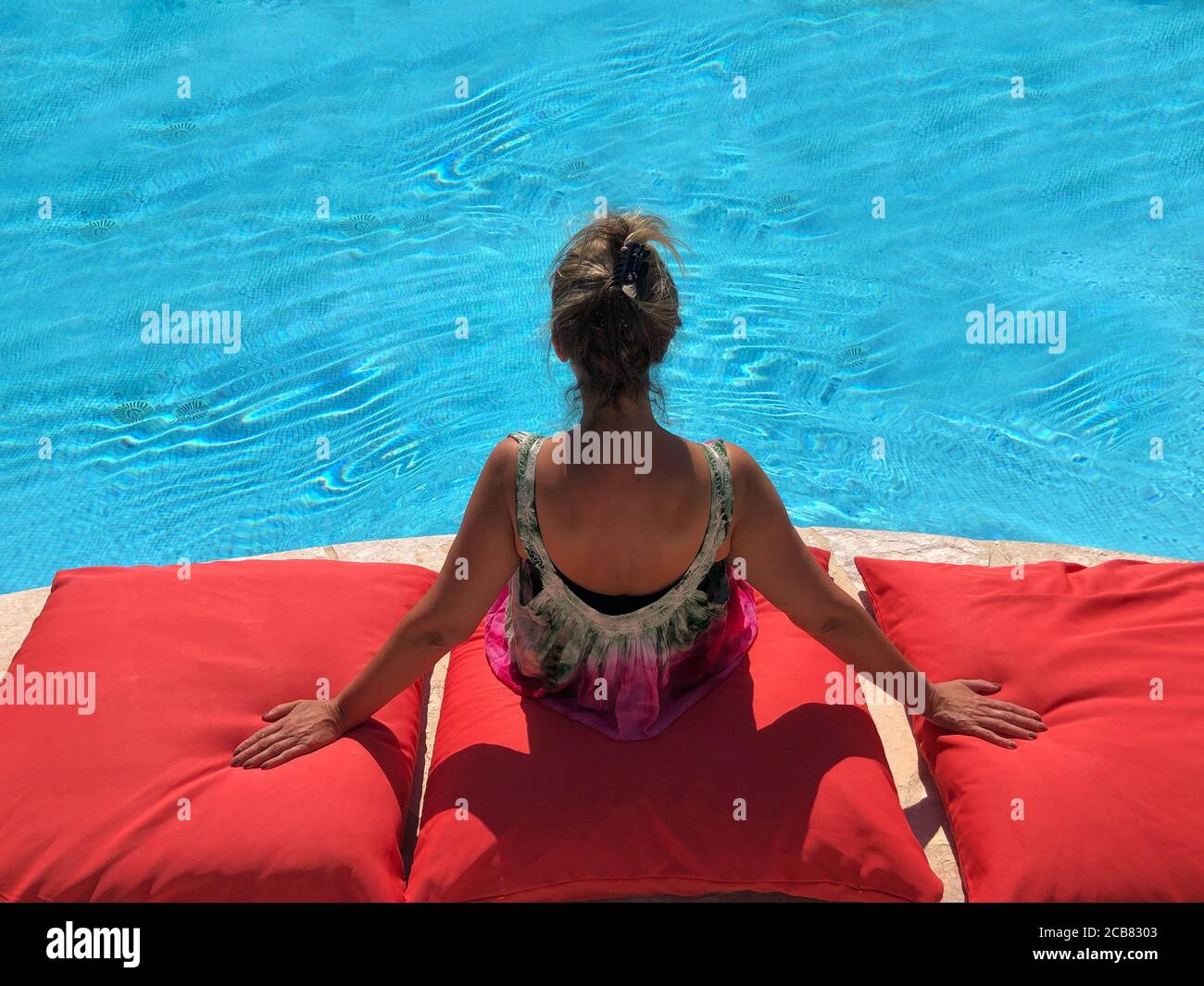 Rückansicht einer Frau, die an einem Pool sitzt Paddeln Stockfoto