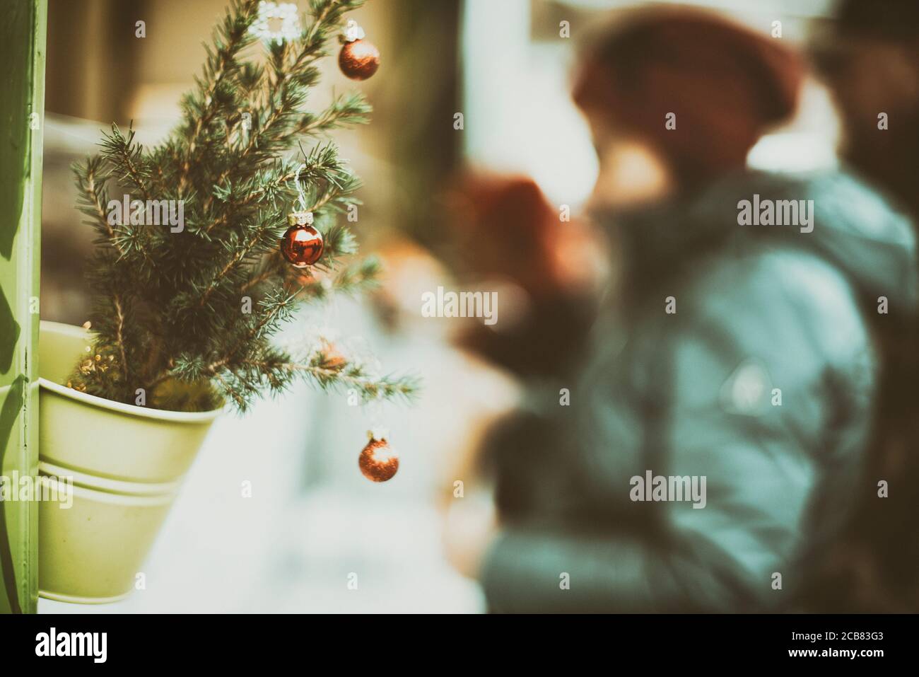 Frau, die bei einer mit Weihnachtskugeln geschmückten Pflanze steht, Elsass, Frankreich Stockfoto