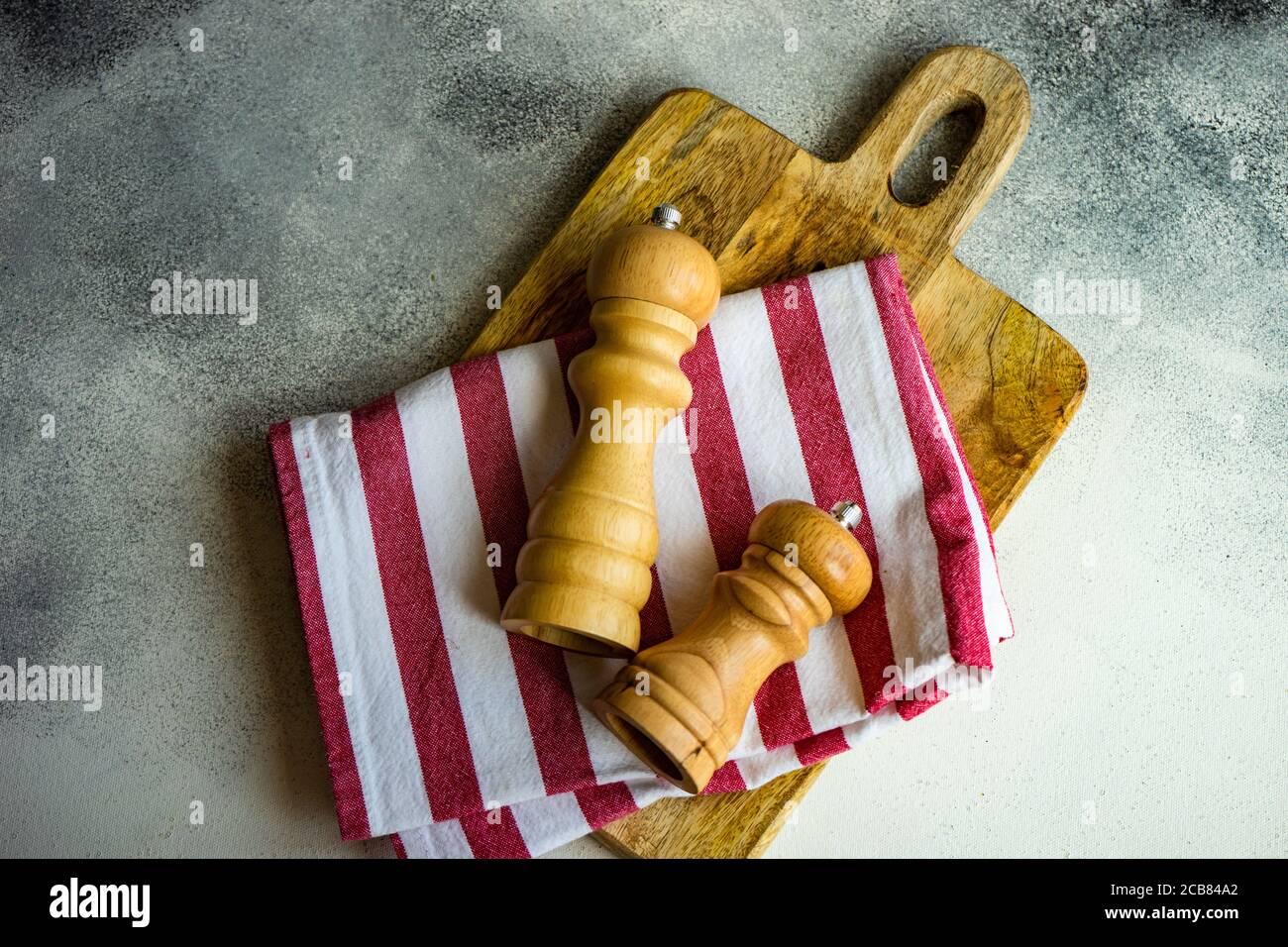 Salzkeller und Pfeffermühle mit einer Serviette auf einem Schneidebrett Stockfoto