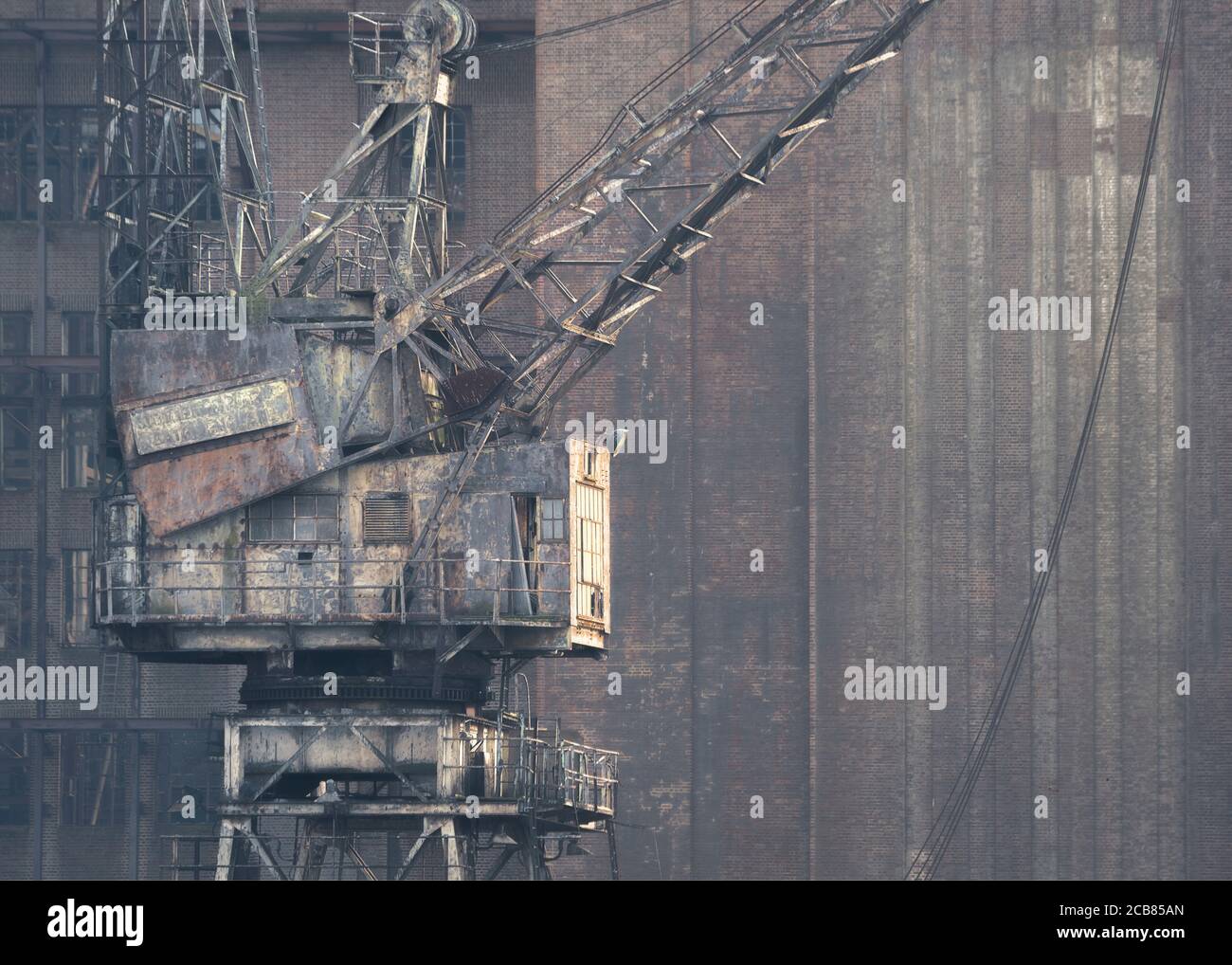 Alter rostiger Kran vor einem verlassenen Fabrikgebäude, Großbritannien Stockfoto