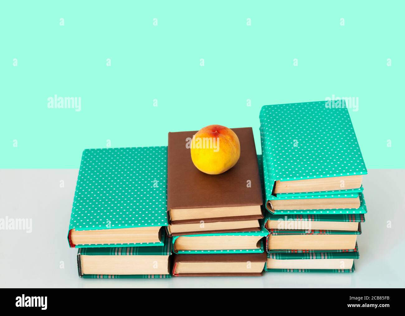Zurück in die Schule, Stapel von Büchern in bunten Abdeckungen und Pfirsich auf Holztisch mit grünen Minze Hintergrund. Fernhausbildung.Quarantine Konzept der s Stockfoto