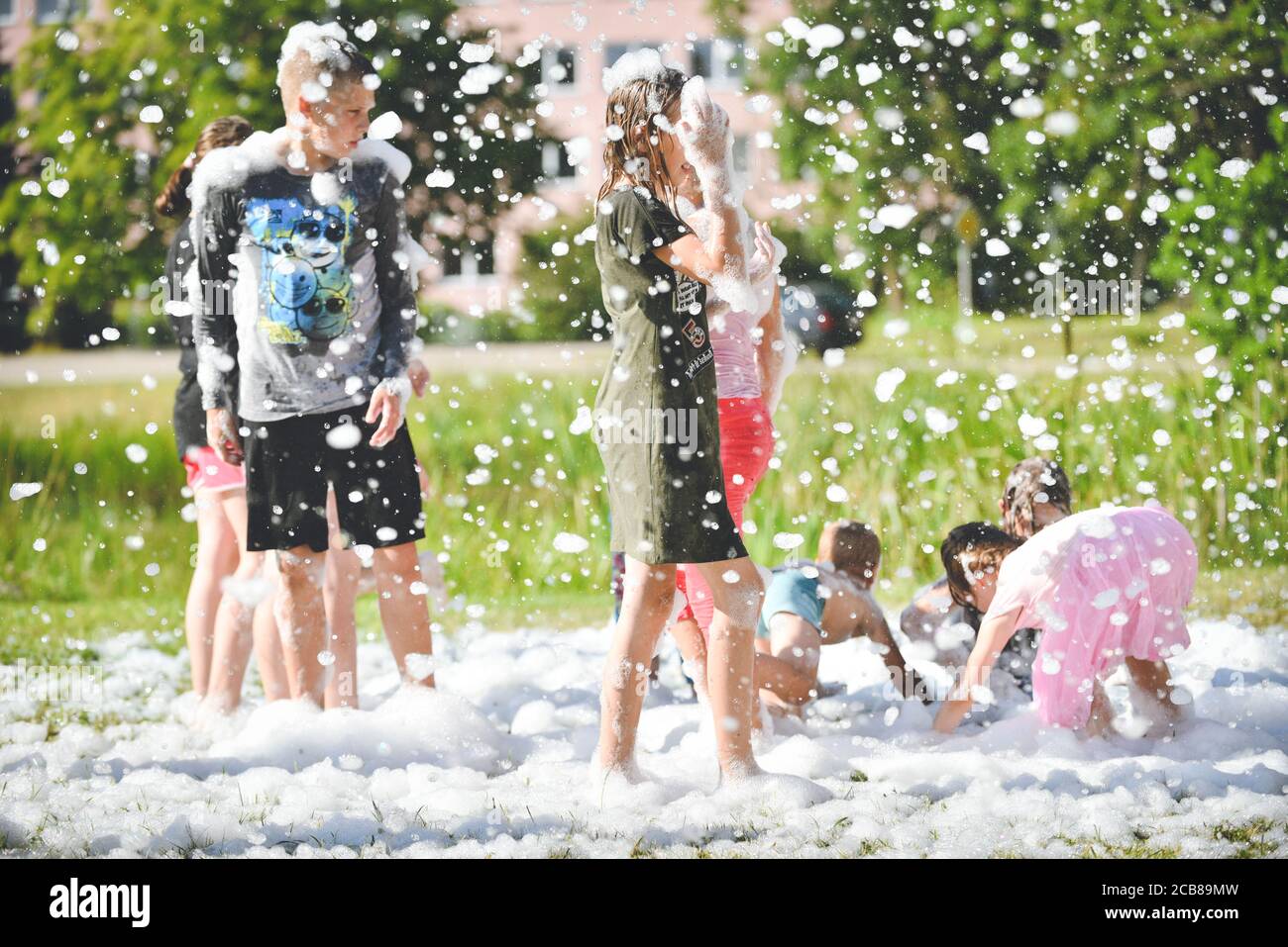 Junge Leute im Schaum. Eine Schaumparty. Gruppe von Kindern, die Spaß haben, genießen und tanzen auf einer Schaumparty im Aquapark. Außenansicht der Schaummaschine. Stockfoto