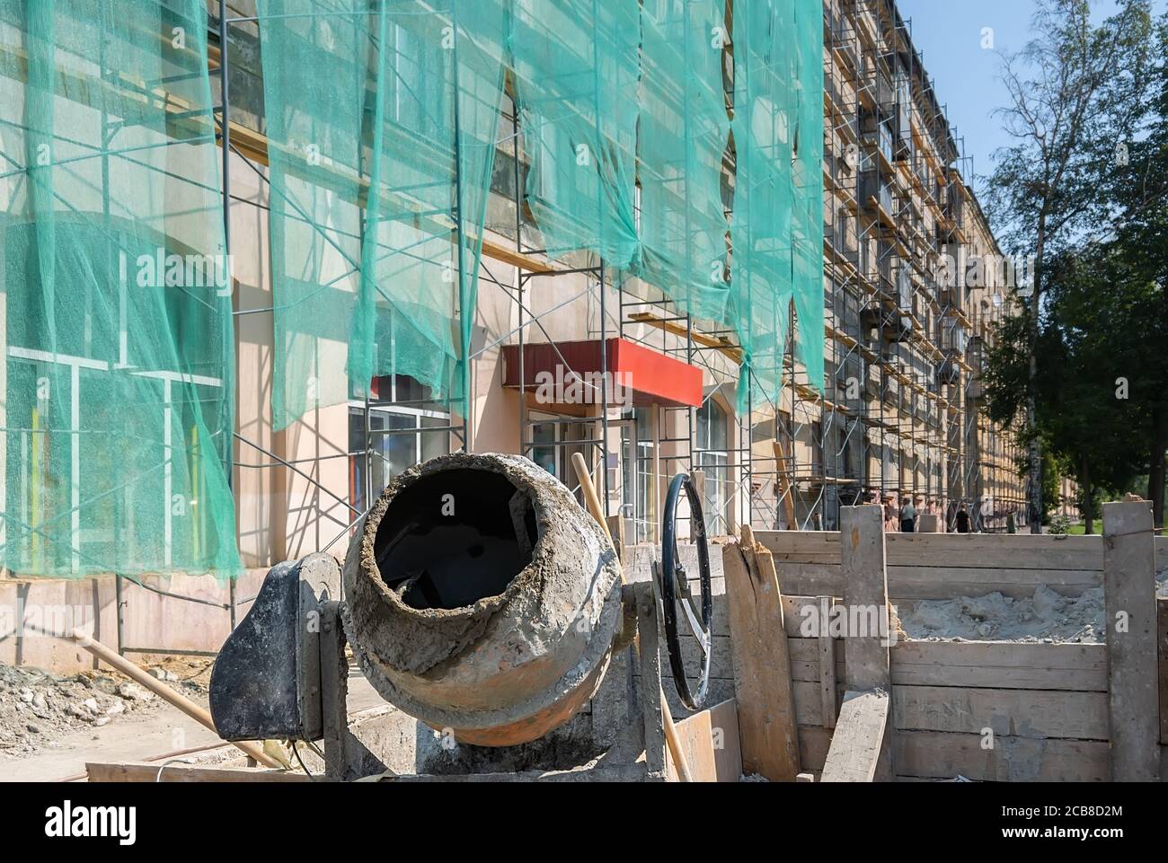 In der Nähe des zu reparierenden Gebäudes steht ein Betonmischer Stockfoto