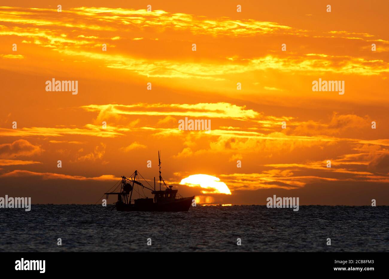 Ein Fischtrawler, der sich im Bild der Sonne über dem Gormanston Strand in der Grafschaft Meath aufzieht. Stockfoto