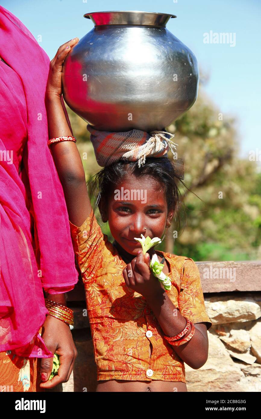 Charming Indian Mädchen aus armen Familie mit traditionellen Wassertopf auf dem Kopf. Indien, Rajasthan. feb 2013 Stockfoto