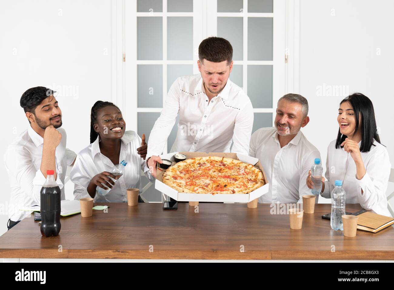 Mittagspause. Junge Mitarbeiter bestellten Pizza ins Büro und essen gemeinsam in ihrem Büro zu Mittag Stockfoto