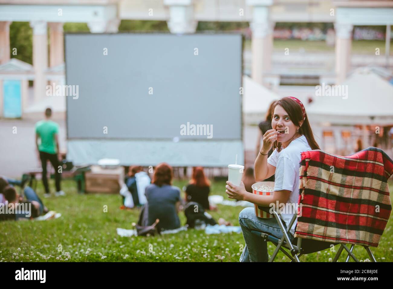 Frau, die im Campingstuhl sitzt und Film im Open Air Kino sieht Stockfoto