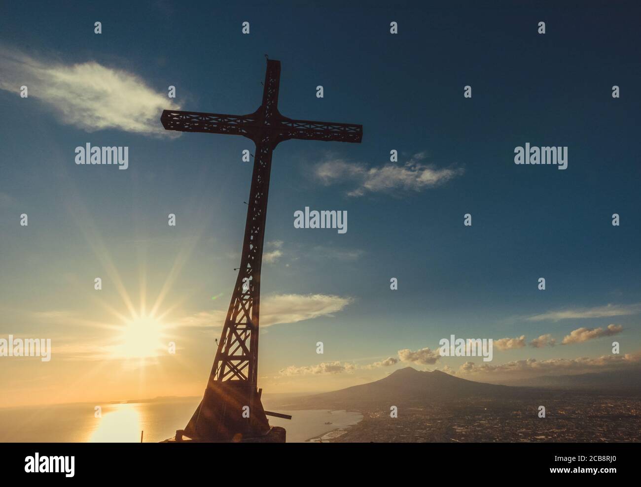 Kreuz aus Stahl über dem Golf von Neapel, mit Blick auf den vesuv und Sonnenuntergang mit warmem Licht. Stockfoto