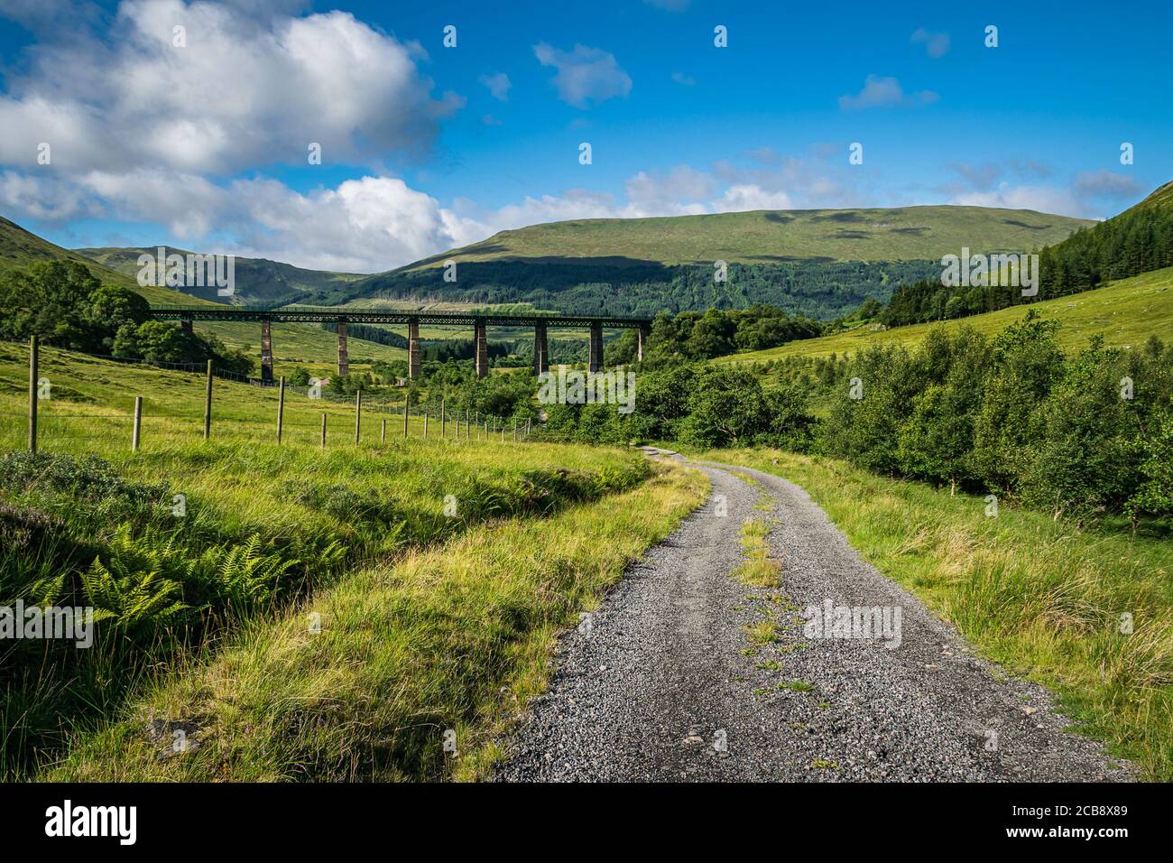 Fahren Sie Glen auch in den schottischen Highlands hinauf mit dem Zugviadukt am Horizont. Wunderschöne schottische Sommerlandschaft. Stockfoto