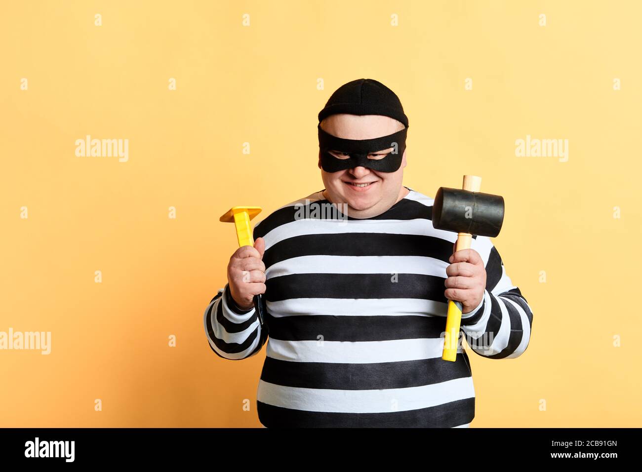 Plump Dieb mit Hammer isoliert auf gelbem Hintergrund, Nahaufnahme Porträt Stockfoto