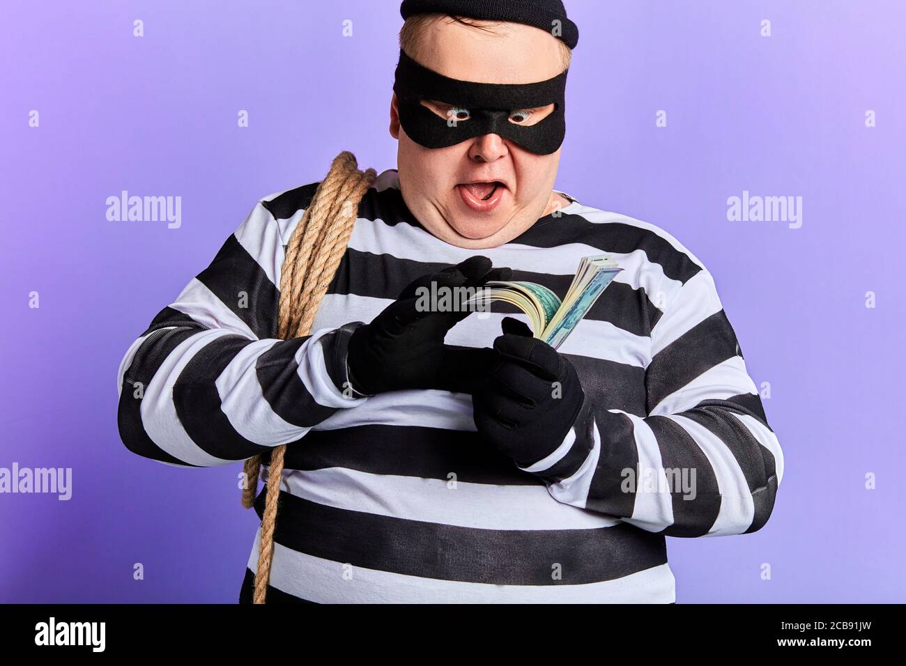 Glücklich aufgeregt fetten jungen Mann mit einem Seil auf seiner Schulter hält Geld, es zu zählen. Nahaufnahme Porträt. Isoliert blauen Hintergrund. studio erschossen Stockfoto