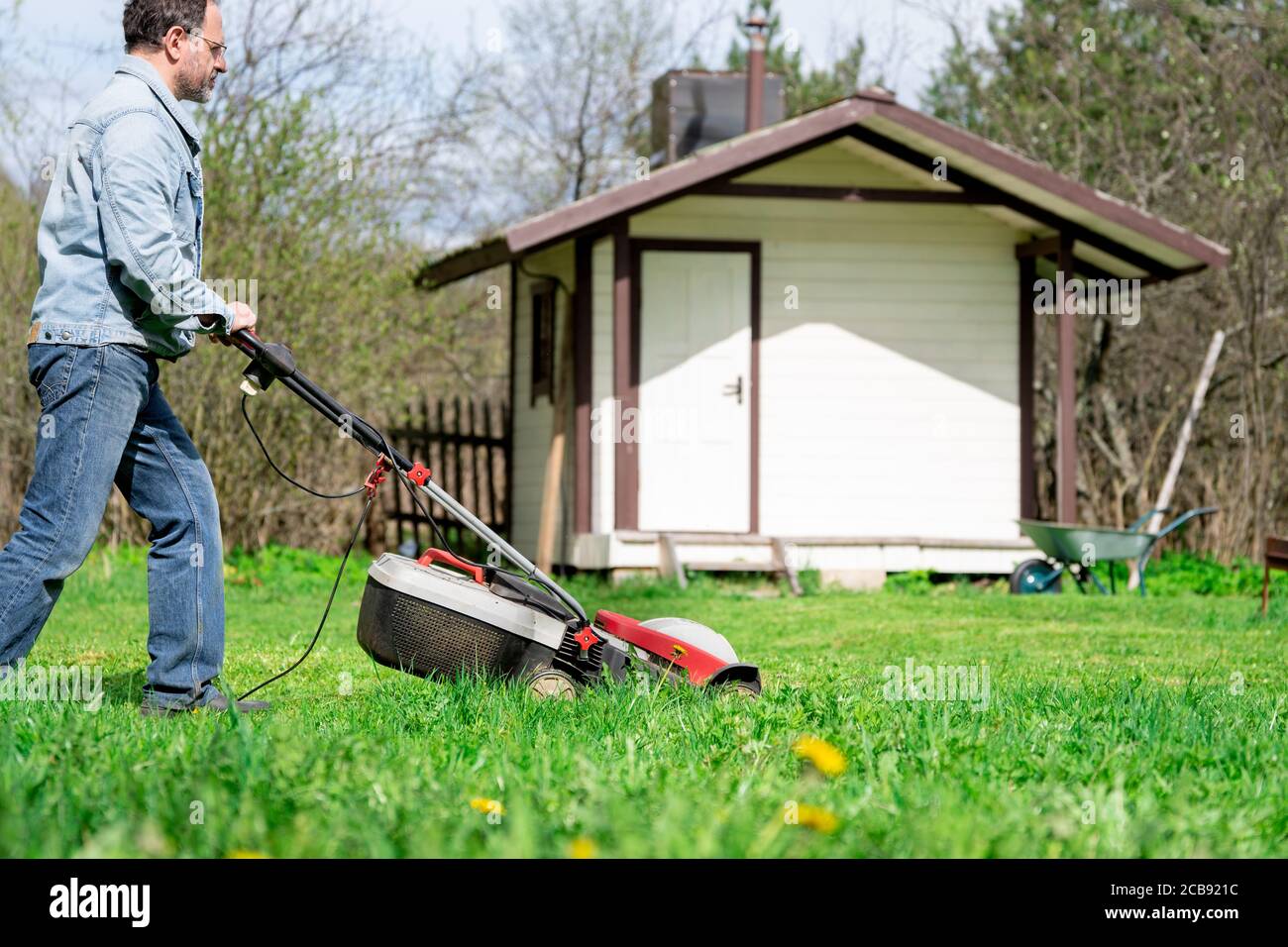 Mann schneidet Gras mit einem Rasenmäher auf dem Hinterhof Stockfoto
