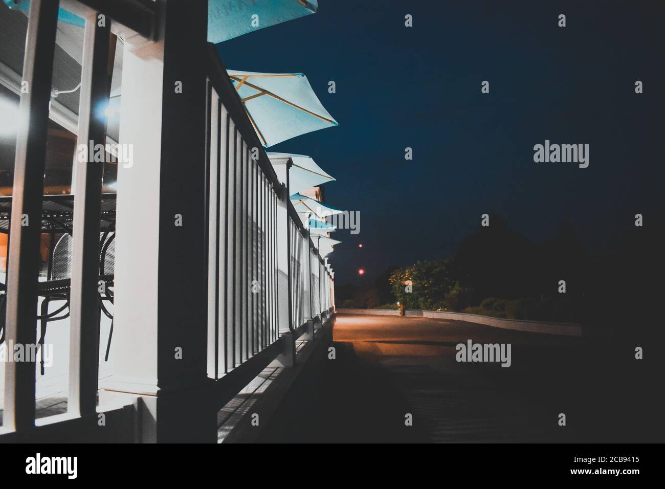 Eine Reihe von hellblauen Schirmen auf einem gut gemachten Holz Deck Stockfoto