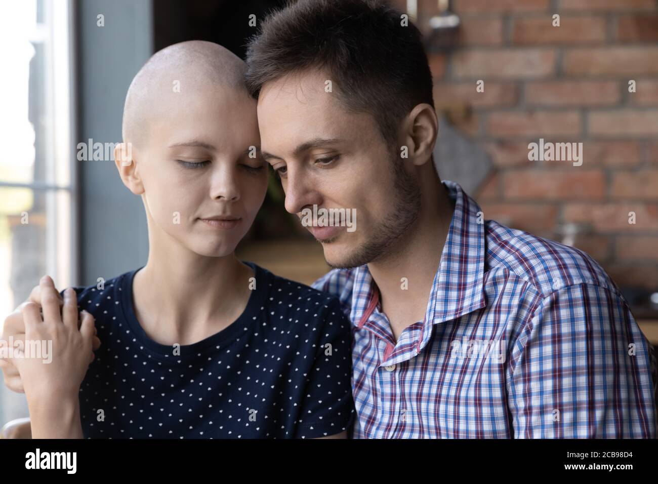 Fürsorglicher Ehemann Umarmung Unterstützung kranke junge haarlose Frau Stockfoto