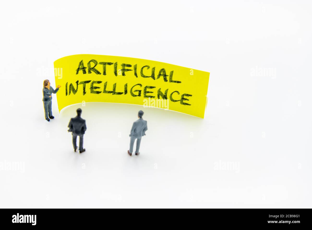 Präsentationstreffen mit Miniaturfiguren, die als Geschäftsleute stehen Vor Post-it-Notiz mit Künstlicher Intelligenz handgeschriebenes Durcheinander Stockfoto