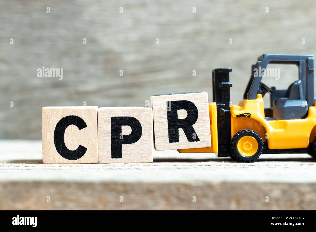 Spielzeug Gabelstapler halten schreiben Block R zu Wort (Abkürzung der kardiopulmonalen Reanimation) auf Holz Hintergrund abgeschlossen Stockfoto