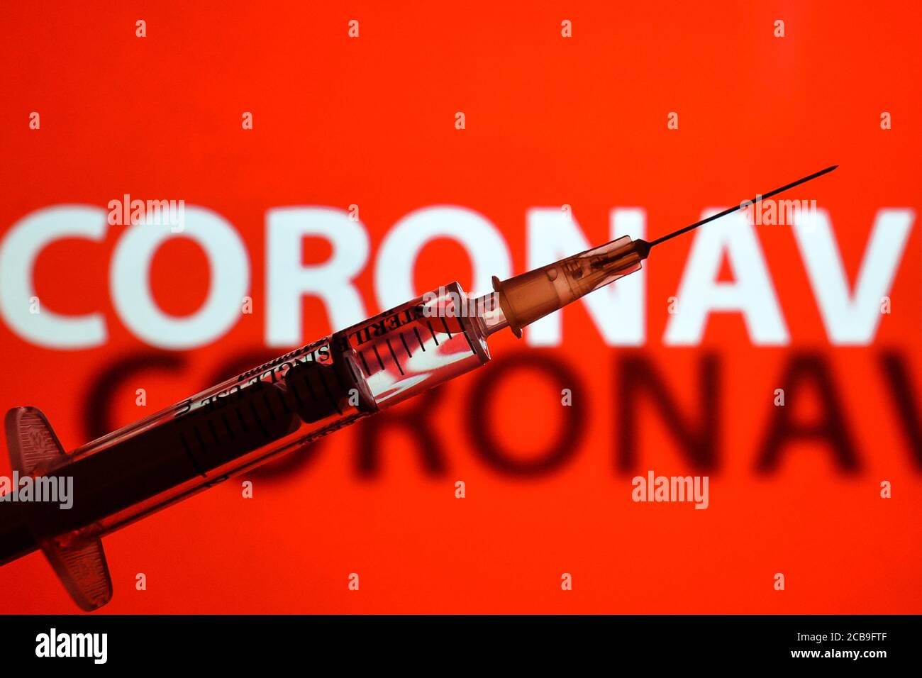 In dieser Fototafel eine medizinische Spritze und 'Coronavirus' Inschrift im Hintergrund. Stockfoto