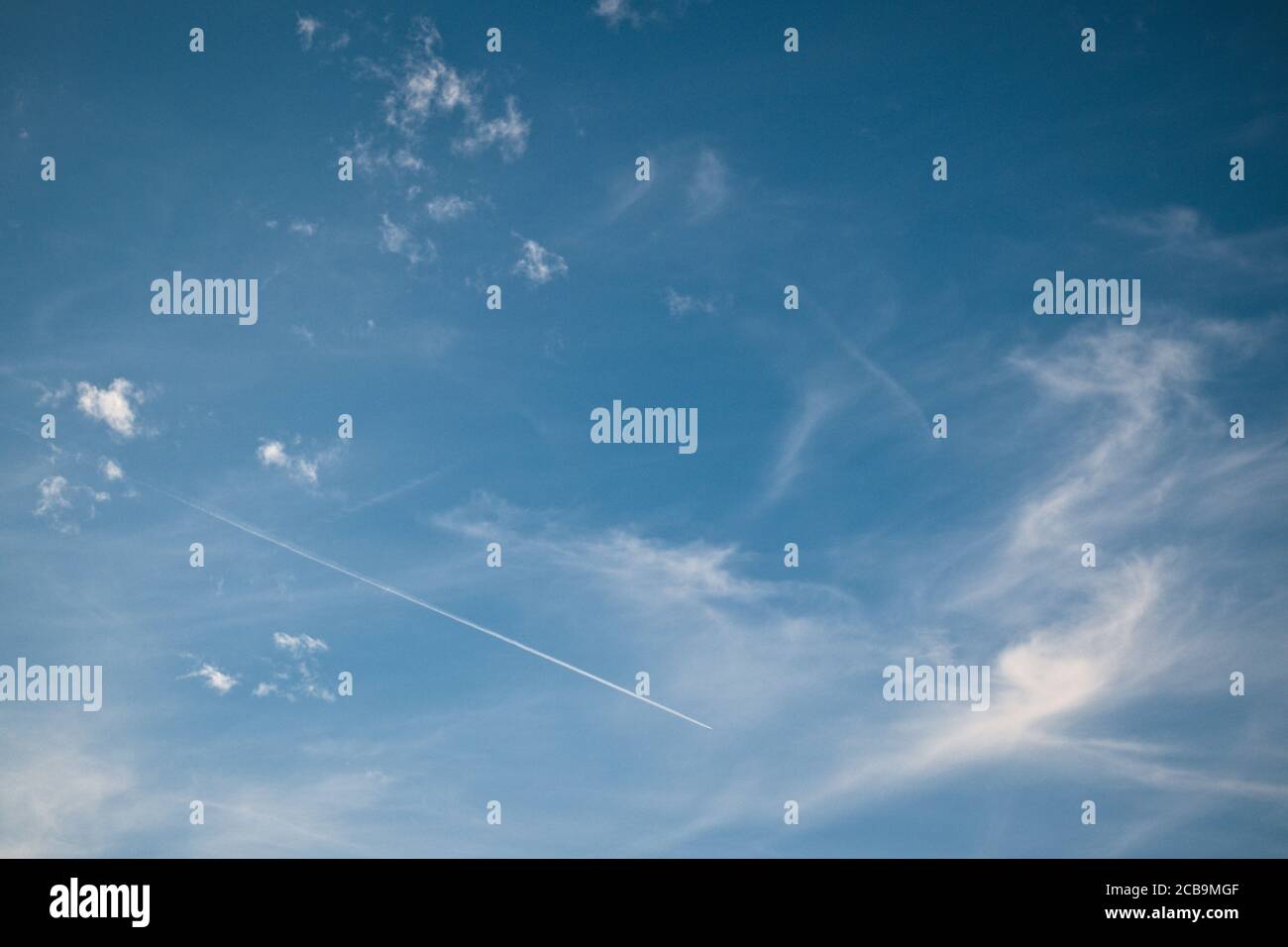 Leichte, wispy Wolken am tiefblauen Himmel mit dem Jet-Stream eines Flugzeugs Stockfoto