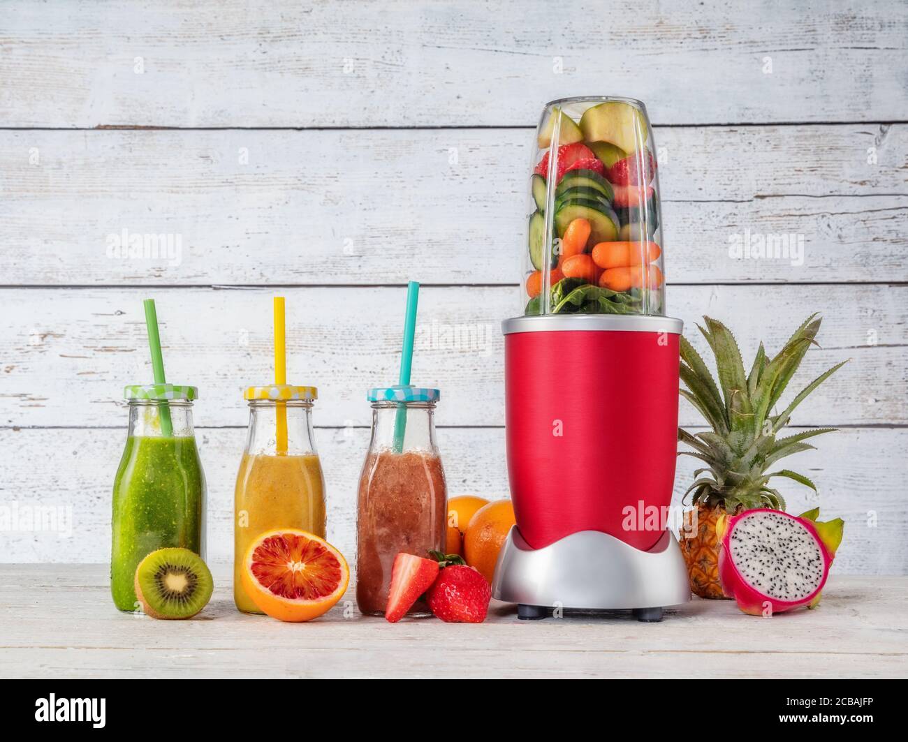 Smoothie Maker Mixer mit Fruchtstücken Zutaten, im Interieur aus Holz gelegt. Gesundes Getränk und Lebensstil Stockfoto
