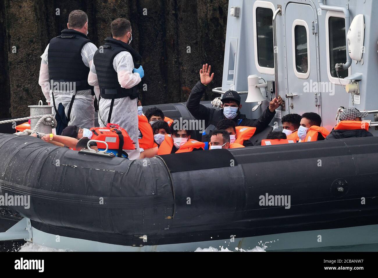 Eine Gruppe von Menschen, die als Migranten gedacht werden, eine winkt, werden von Grenzbeamten nach einer Reihe von kleinen Bootsvorfällen im Kanal heute in Dover, Kent, gebracht. Stockfoto