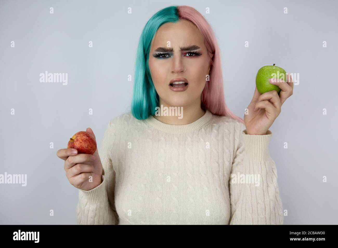 Junge Frauen mit gefärbten Haaren in blauen und rosa Farben Und hält grüne und rote Äpfel Stockfoto