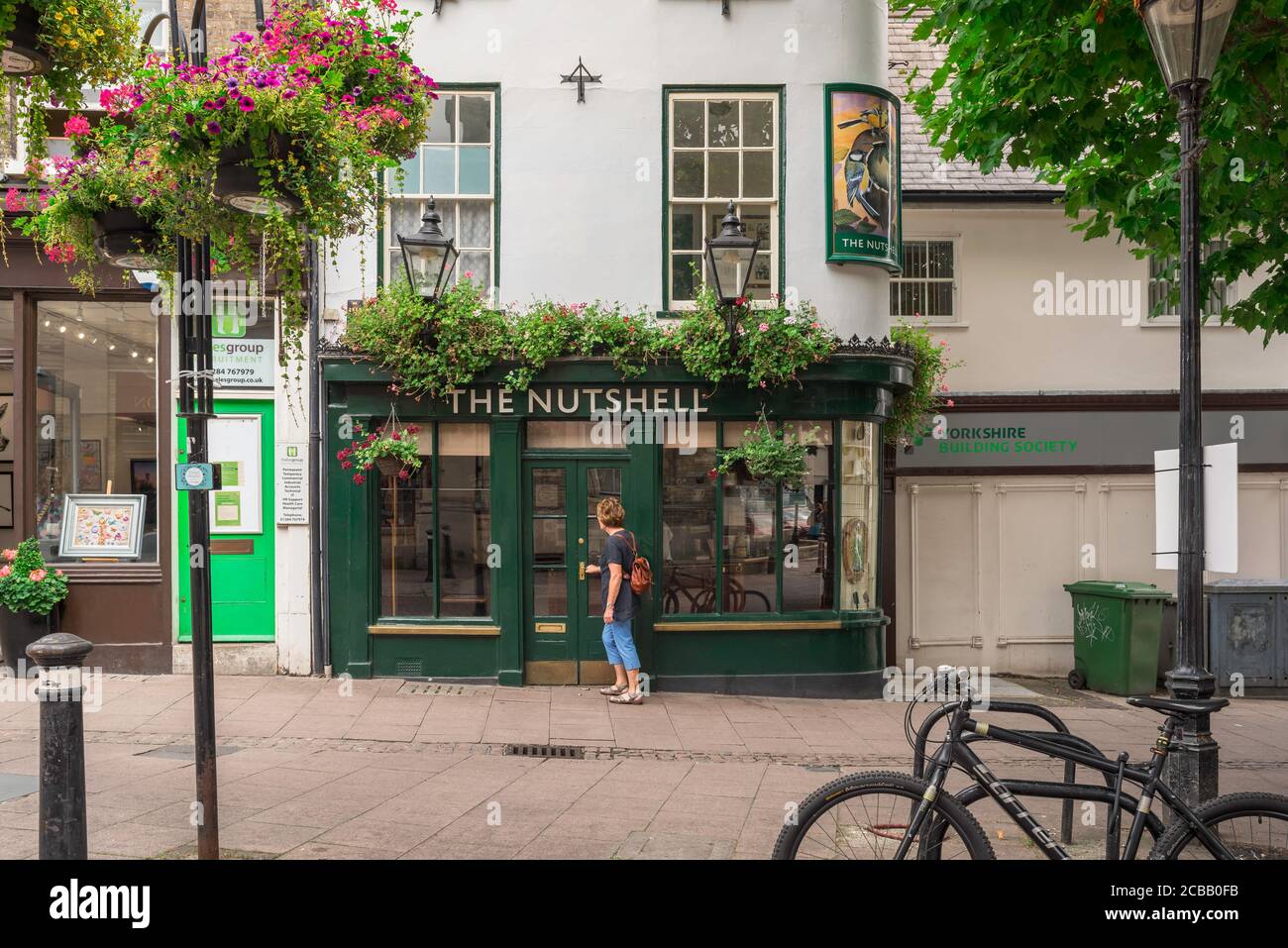 Nussschale Bury St Edmunds, Ansicht einer Frau, die den Nutshell Pub in Bury St Edmunds, Suffolk, betritt, behauptete, das kleinste öffentliche Haus in England zu sein. Stockfoto