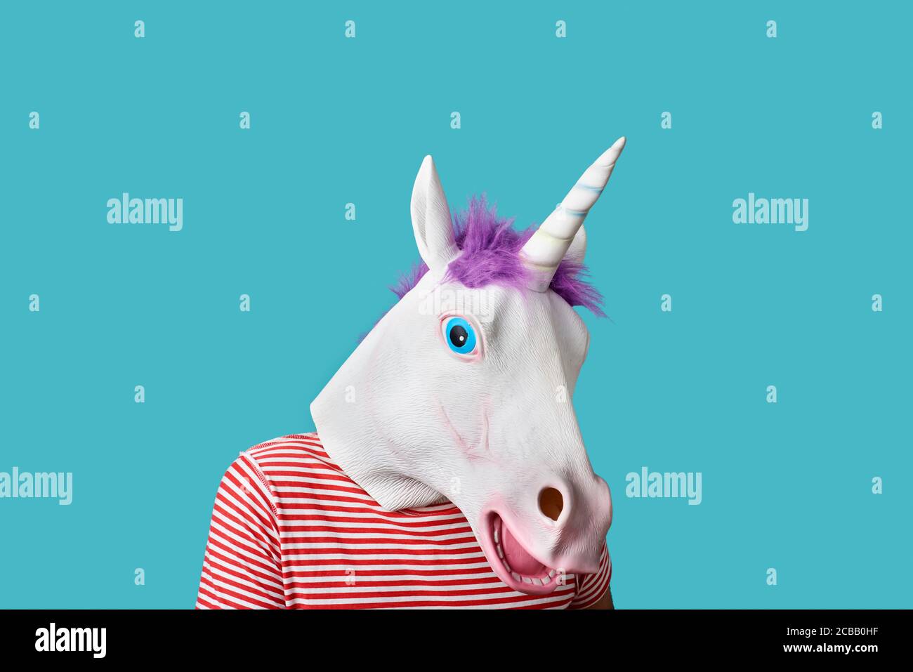 Mann mit Einhorn-Maske und rot-weiß gestreiftem T-Shirt auf blauem Hintergrund mit leerem Raum um ihn herum Stockfoto