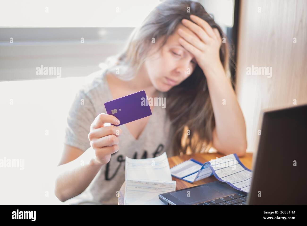 Besorgt und verzweifelt Frau mit Rechnungen und Kreditkarte Stockfoto