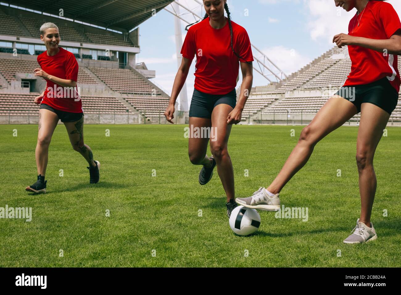 Eine Gruppe von Frauen, die auf dem Spielfeld Fußball spielen, um den Ball zu spielen. Weibliche Fußballspieler laufen auf dem Feld für den Besitz des Balls. Stockfoto