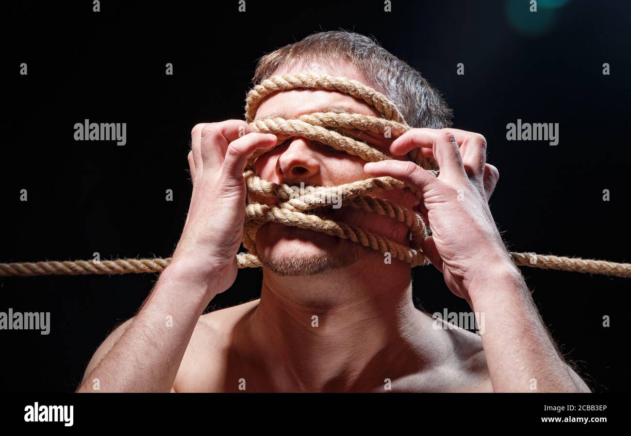 Foto von gebundenem Mann mit Seil und Händen auf dem Gesicht Stockfoto