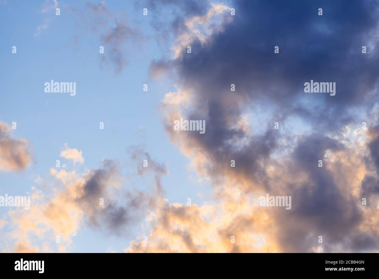 Blauer Himmel mit goldenen und dunklen Wolken. Himmlisch verträumt flauschig bunte Fantasy-Wolken. Stockfoto