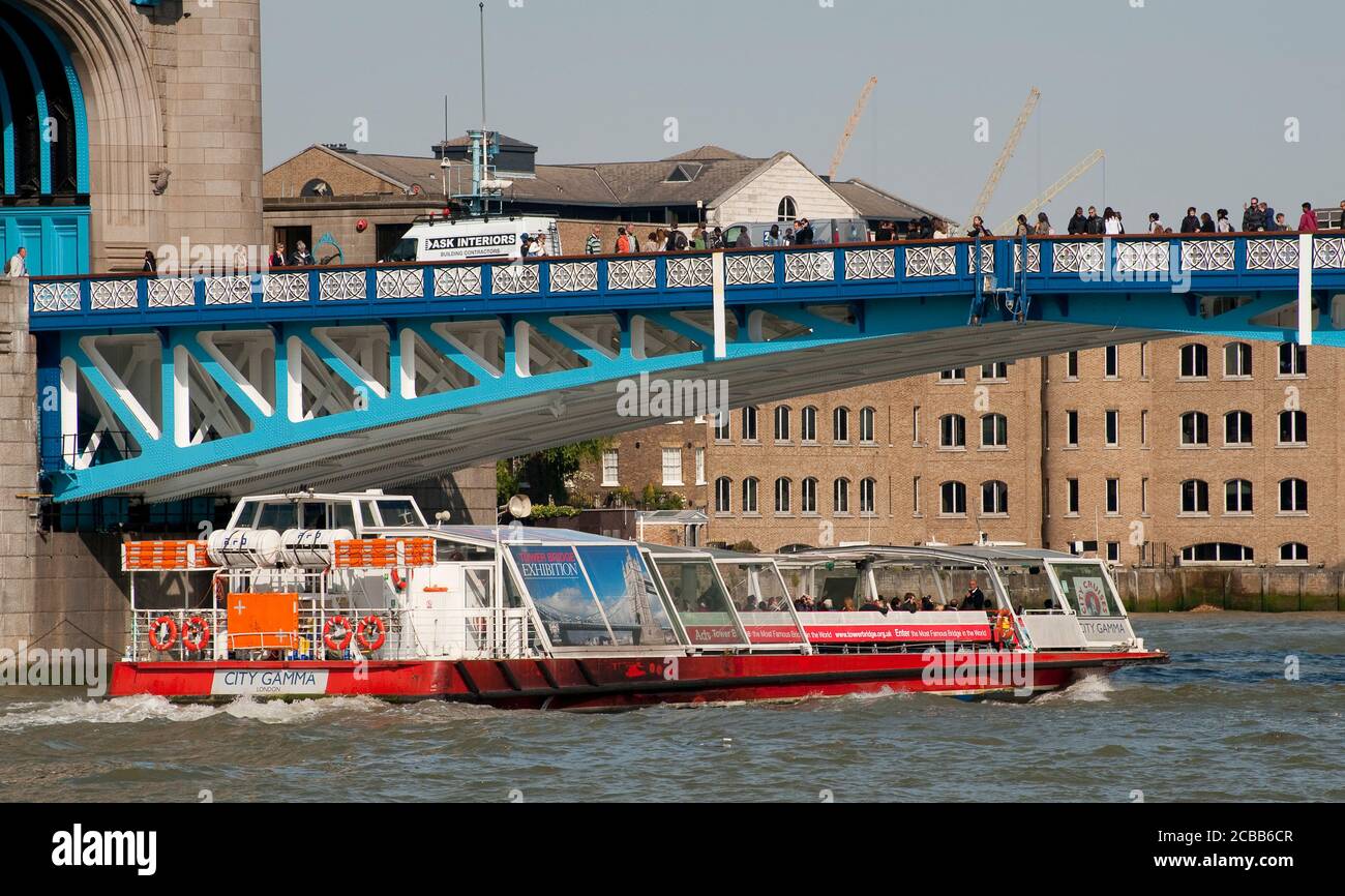 Flusskreuzfahrtschiff, der unter der Tower Bridge vorbeifährt, einer ikonischen Brücke über die Themse in London, England. Stockfoto