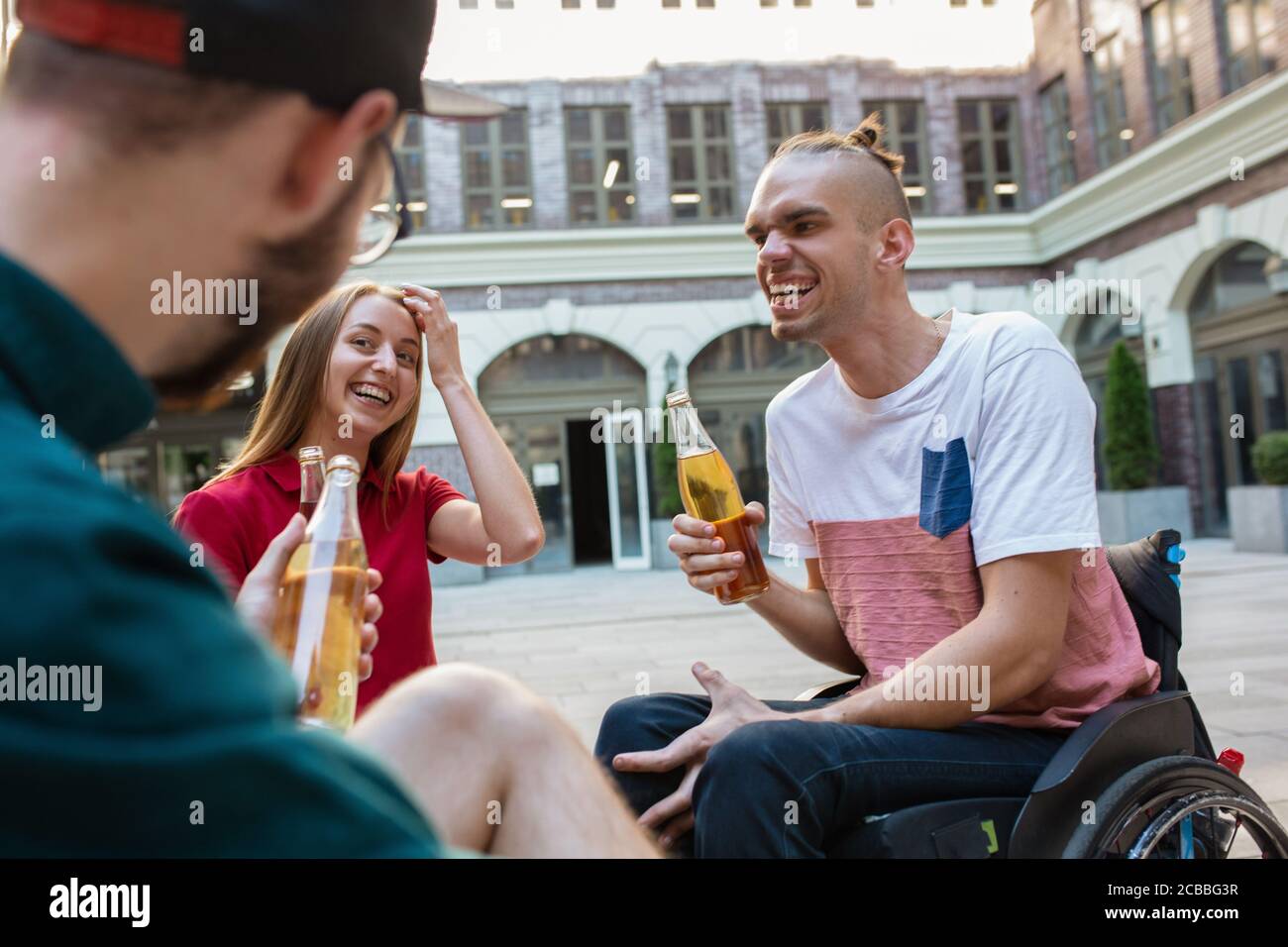 Pizza-Zeit. Eine Gruppe von Freunden, die am Sommertag auf der Straße der Stadt spazieren gehen. Behinderter Mann mit seinen Freunden, die Spaß haben. Inklusion und Diversity-Konzept, normale Lebensweise von besonderen Gruppen der Gesellschaft. Stockfoto