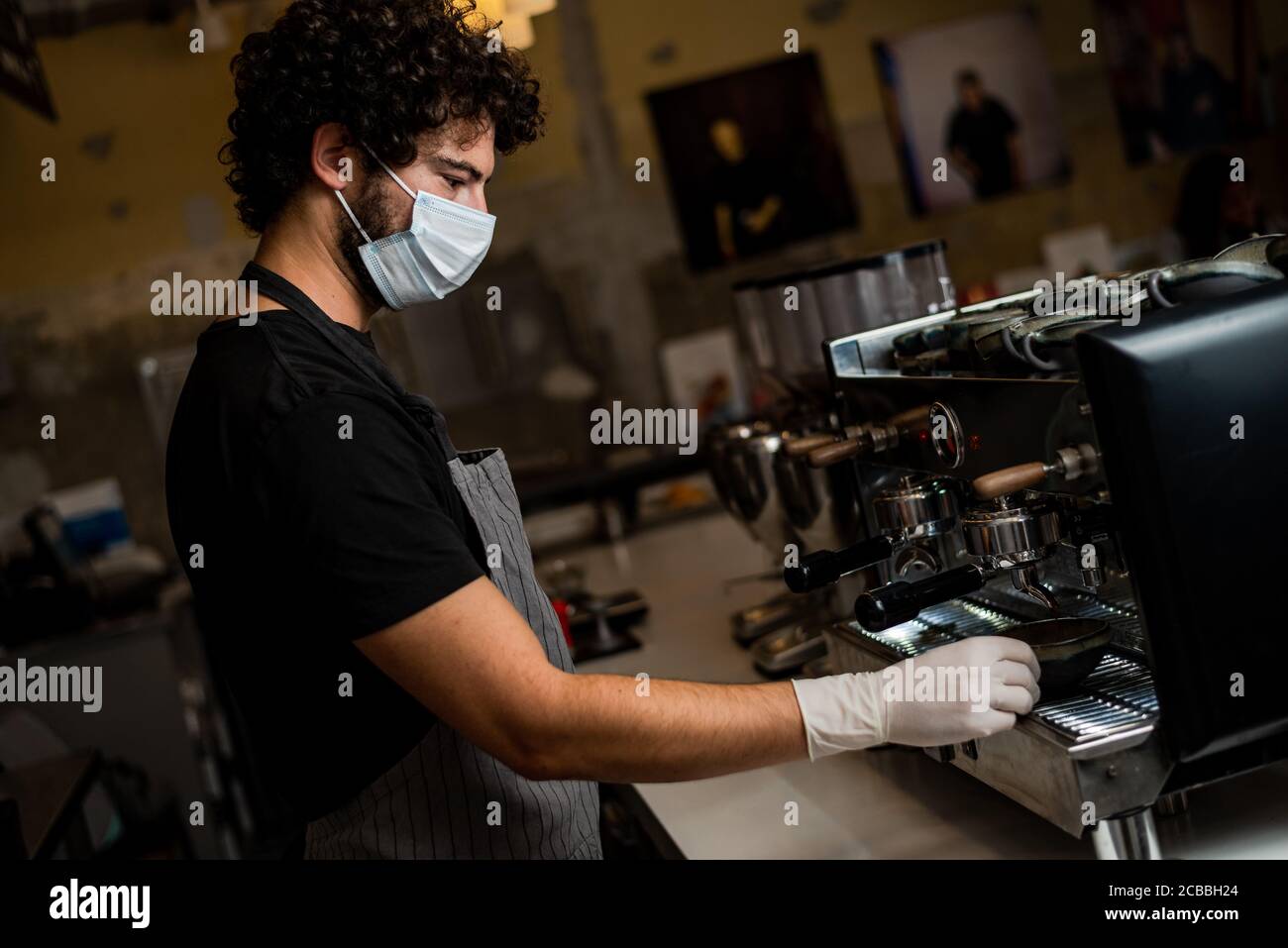 Junger Mann, Barista, Kaffee Espresso beim Tragen einer OP-Maske und Handschuhe zur Verhinderung der Corona-Virus Ausbreitung - Bar Sicherheit Arbeitskonzept. Stockfoto