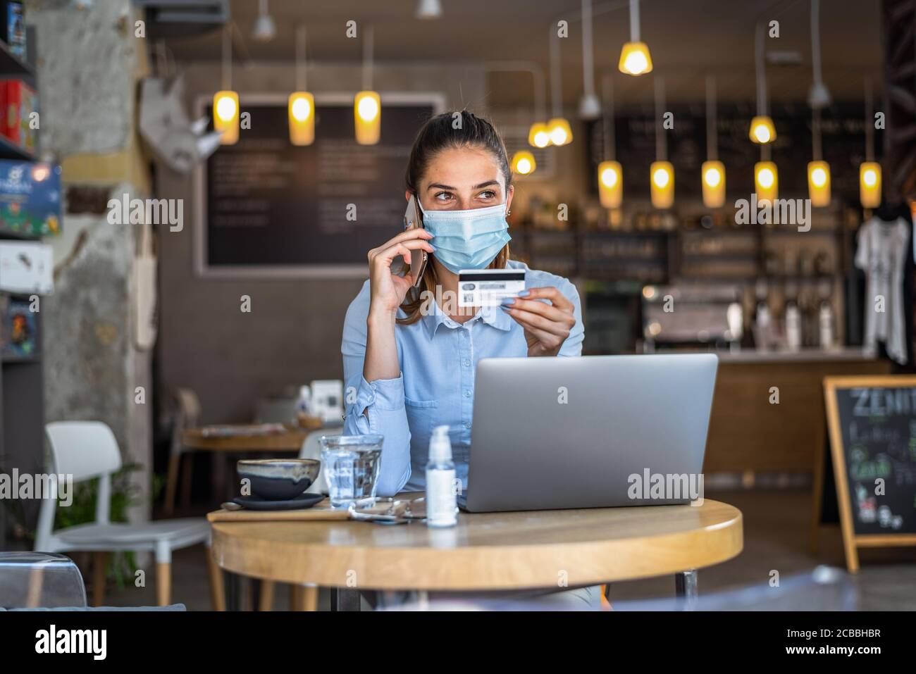 Porträt der jungen Geschäftsfrau trägt Maske beim Online-Shopping und Zahlung mit Kreditkarten. Neuer normaler Lebensstil während der covid-19 Pandemie. Stockfoto