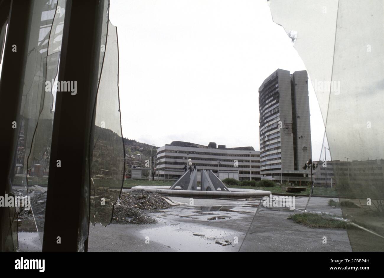 12. April 1994 während der Belagerung von Sarajevo: Das Gebäude der von Gefechten gezeichneten Versammlung wurde durch ein zerbrochenes Fenster des Unis Towers Komplexes betrachtet. Stockfoto