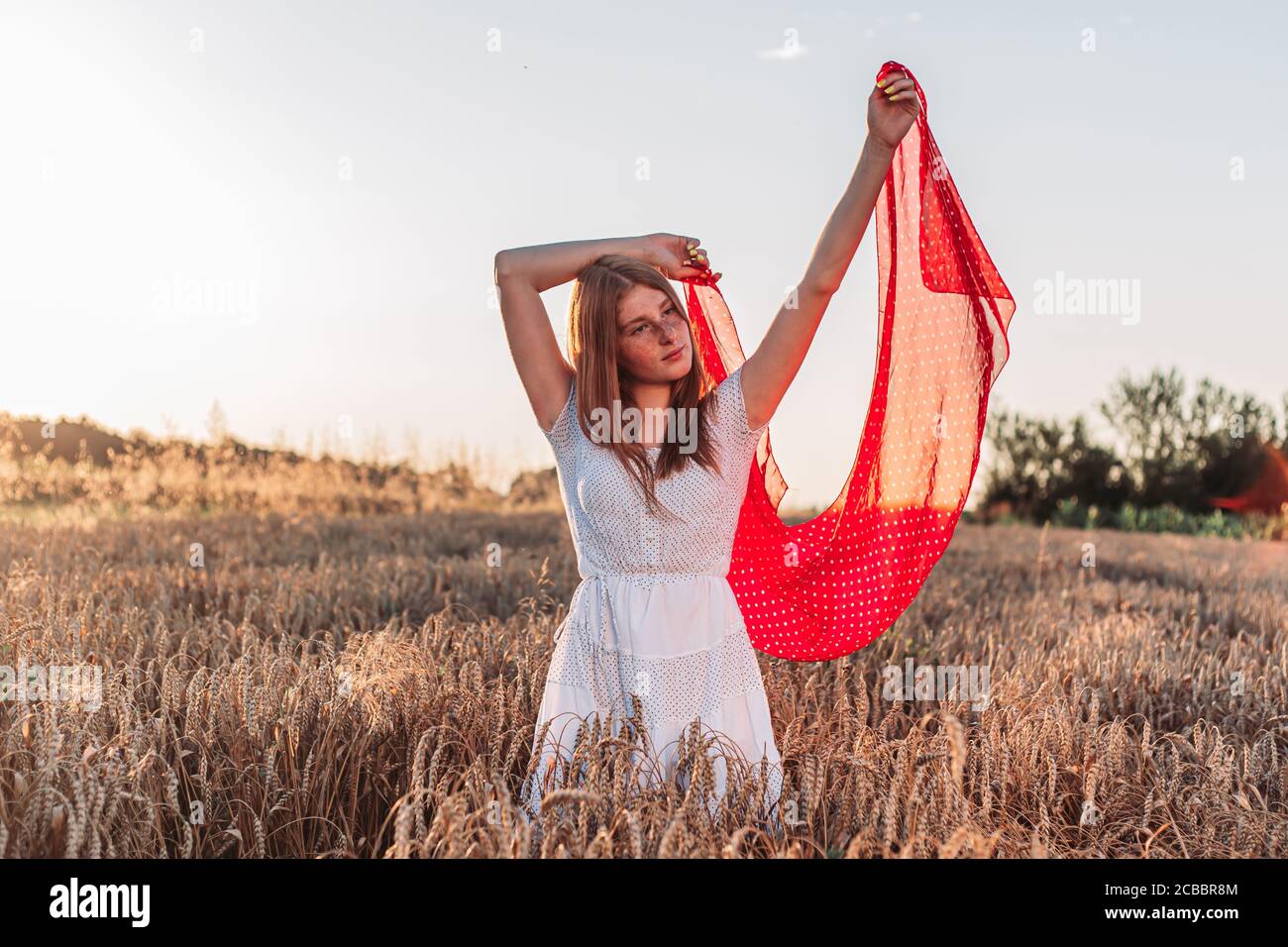 Im Freien Foto von jungen, Ingwer Mädchen in weißem Kleid hält einen roten Schal flattern in der Luft. Stockfoto