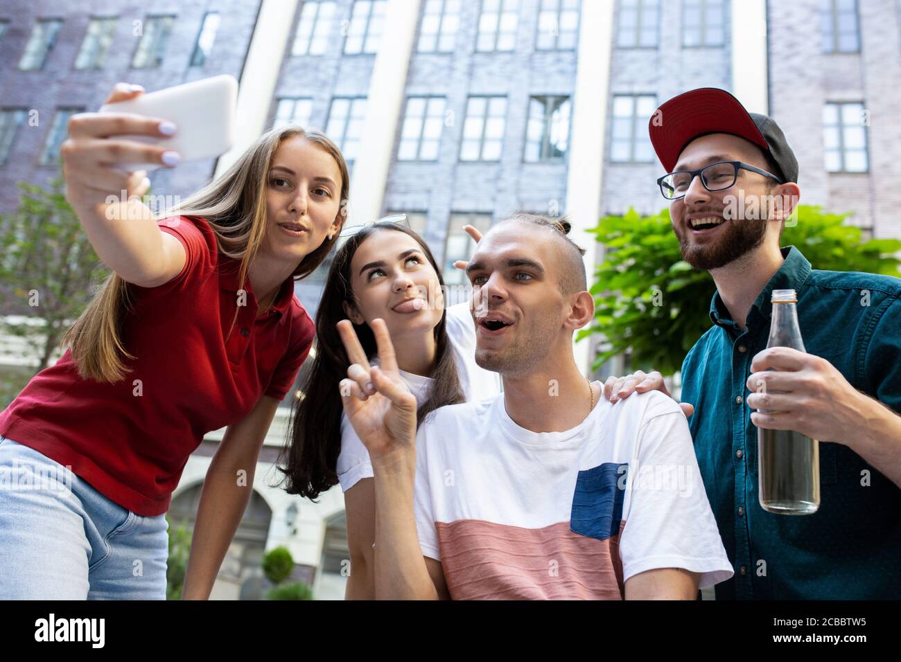 Selfie wird aufgenommen. Eine Gruppe von Freunden, die am Sommertag auf der Straße der Stadt spazieren gehen. Behinderter Mann mit seinen Freunden, die Spaß haben. Inklusion und Diversity-Konzept, normale Lebensweise von besonderen Gruppen der Gesellschaft. Stockfoto