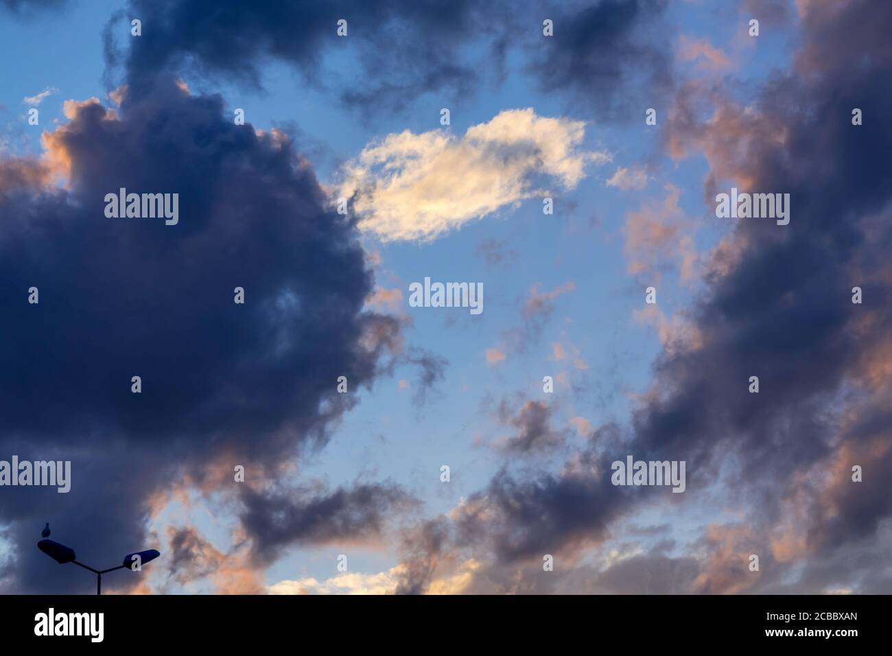 Blauer Himmel mit goldenen und dunklen Wolken. Himmlisch verträumt flauschig bunte Fantasy-Wolken. Stockfoto