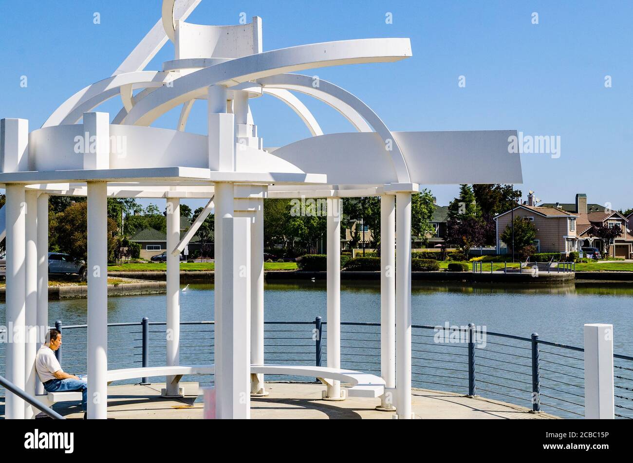 Ein Mann sitzt unter einem hochgeformten modernen Pavillon entlang Das Wasser auf Redwood Shores California USA Stockfoto