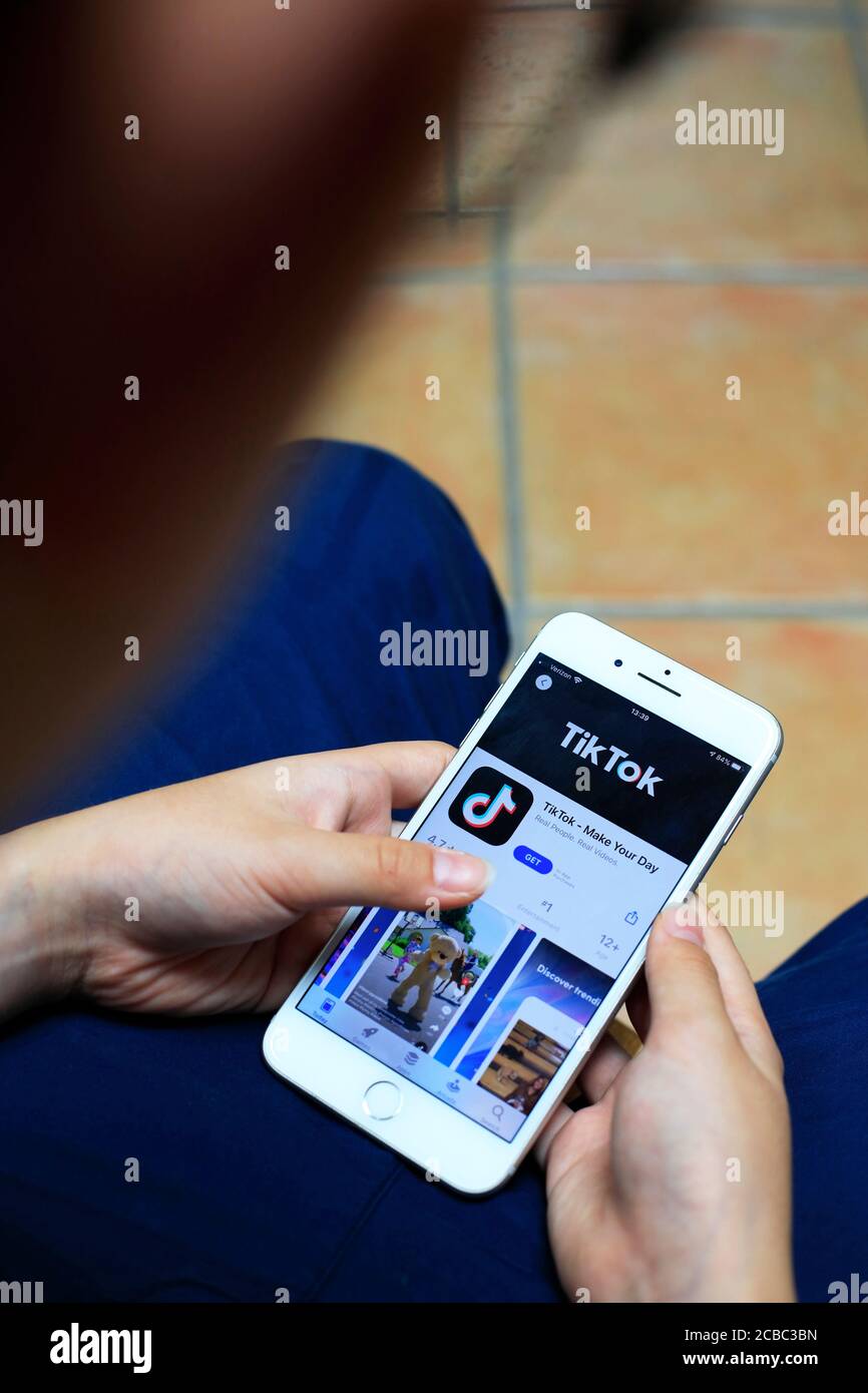 Hände halten ein iPhone mit Tik Tok das Online-Video Teilen und Hosting-App auf dem Bildschirm Stockfoto