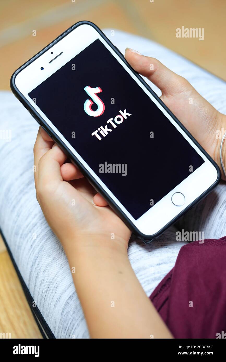 Hände mit einem iPhone mit dem Logo der Online-Video-Sharing Und Hosting-App Tik Tok auf dem Bildschirm Stockfoto
