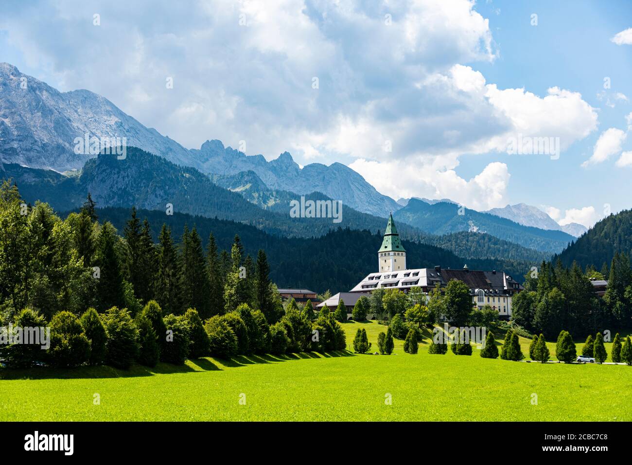 Blick auf das Luxushotel Elmau zwischen der grünen Natur Und die hohen Berge Stockfoto