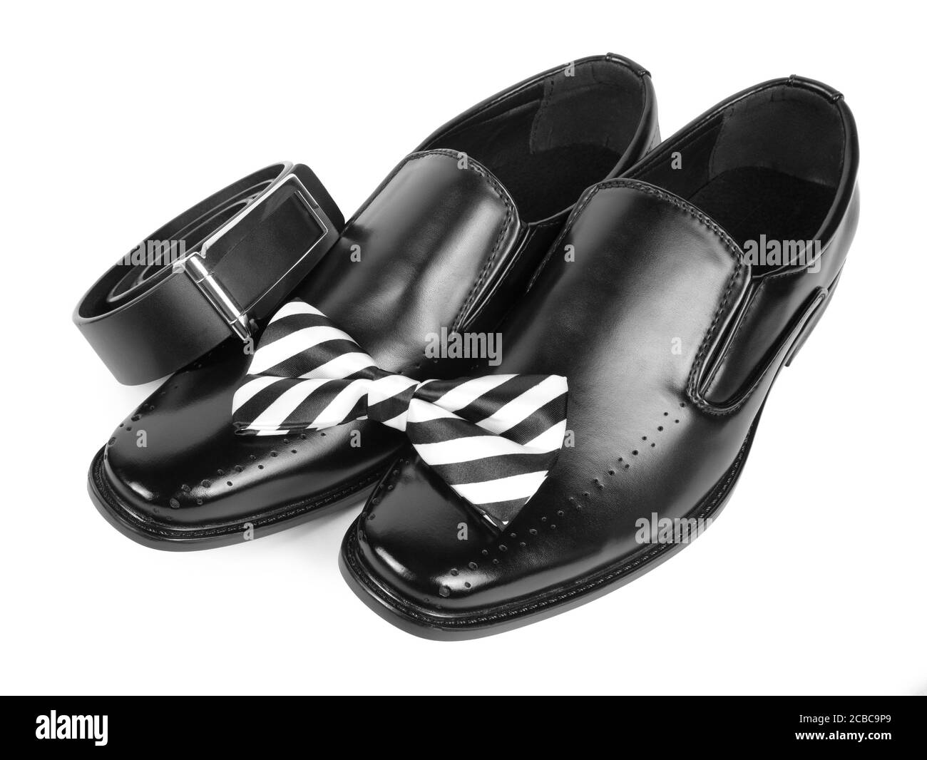 Nahaufnahme von schwarzen männlichen Schuhen, Fliege und Gürtel auf weißem Hintergrund Stockfoto