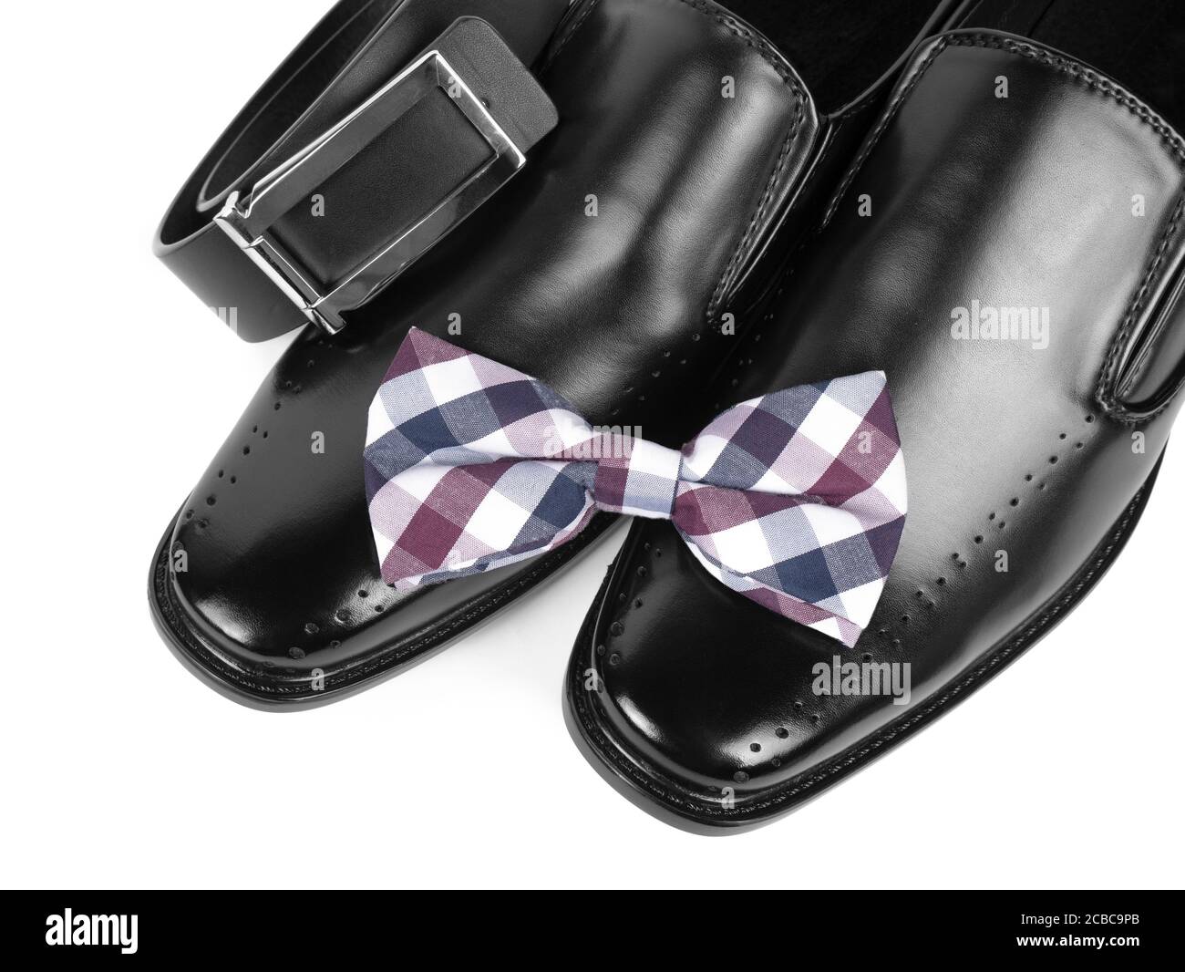 Nahaufnahme von schwarzen männlichen Schuhen, Fliege und Gürtel auf weißem Hintergrund Stockfoto