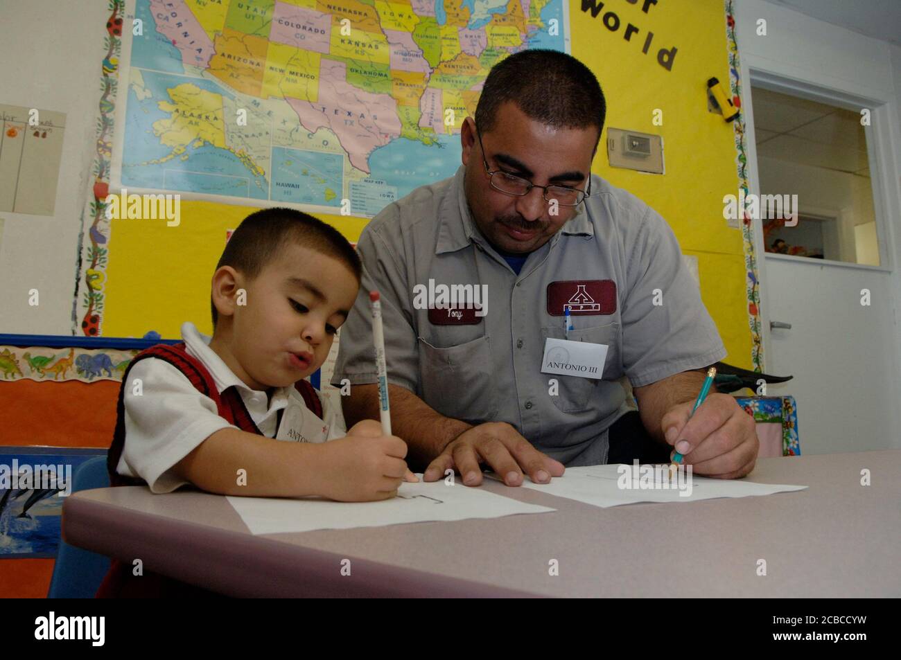 San Antonio Texas USA: Ein Vater aus der Arbeiterklasse und ein Sohn aus dem Kindergarten nehmen an einem Programm in der Vorschule von Head Start Teil, das ein kostenloses Abendessen und Familienzeit für kleine Kinder und ihre Eltern bietet. Nach dem Abendessen treffen sich Erwachsene zu einer Gruppenberatung über Erziehungstechniken und treffen sich dann wieder mit ihren Kindern zusammen, um gemeinsam zu lesen und zu schreiben. © Bob Daemmrich Stockfoto